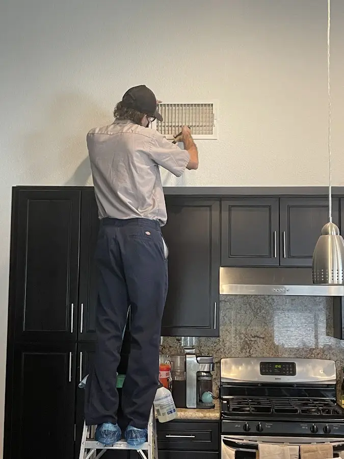 Technician inspecting an air vent during HVAC service in Verona